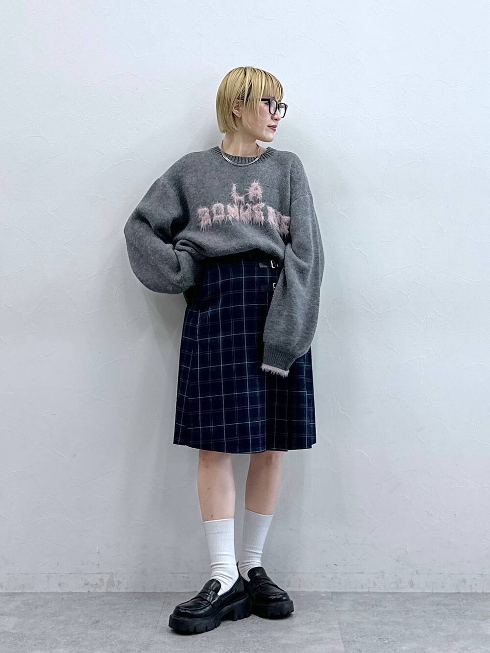 ブラック系のローファー、グレー系のニット/セーター、グリーン系のスカートを着用したレディースの秋コーディネートの4枚目の写真