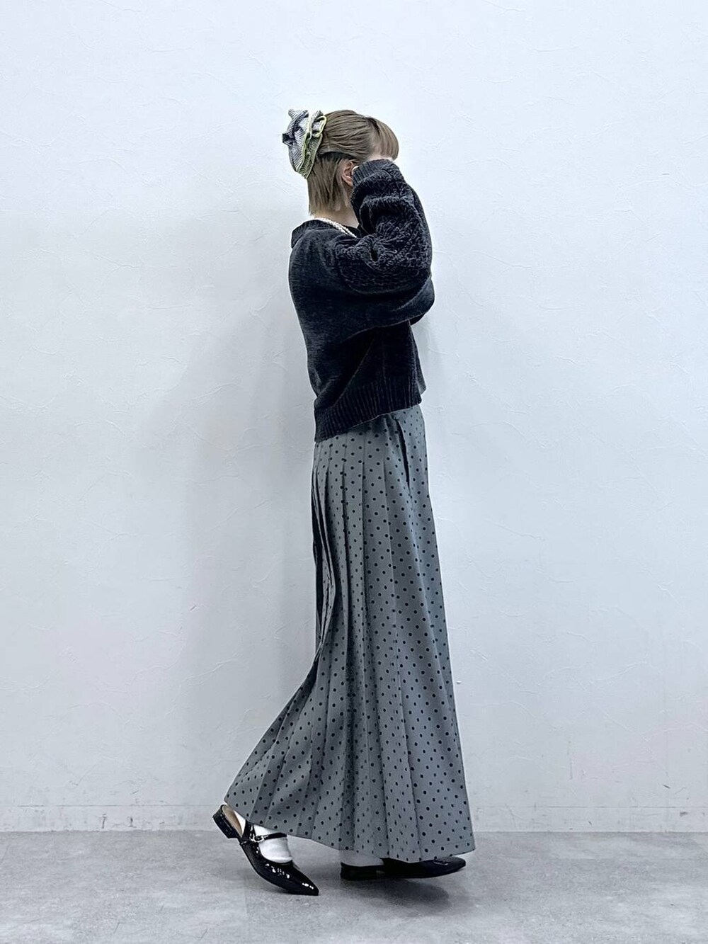 ブラック系のニット/セーター、ブラック系のパンプス、グレー系のスカートを着用したレディースの冬コーディネートの5枚目の写真