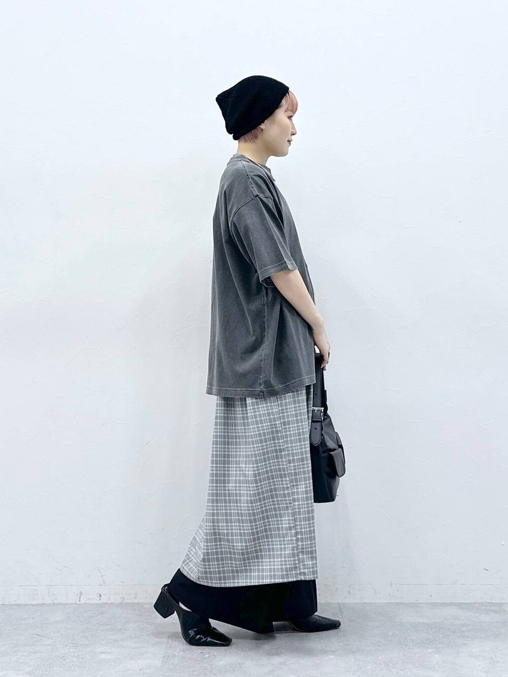 ブラック系のスラックス、グレー系のワンピース、ブラック系のTシャツ/カットソーを着用したレディースの春コーディネートの4枚目の写真