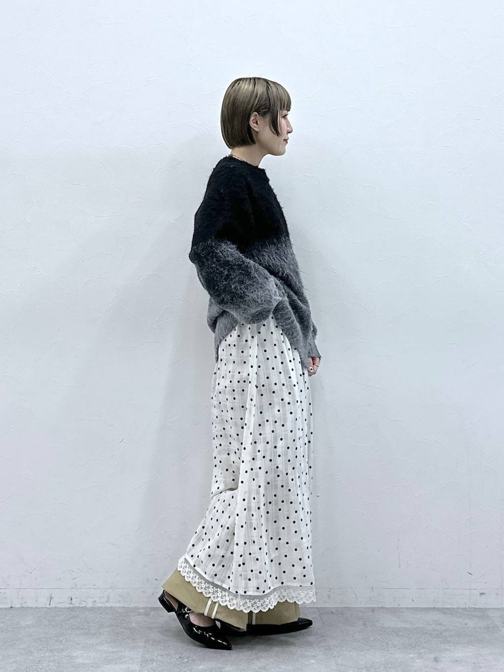 ブラック系のニット/セーター、ブラック系のパンプス、ベージュ系のチノパンツを着用したレディースの冬コーディネートの6枚目の写真