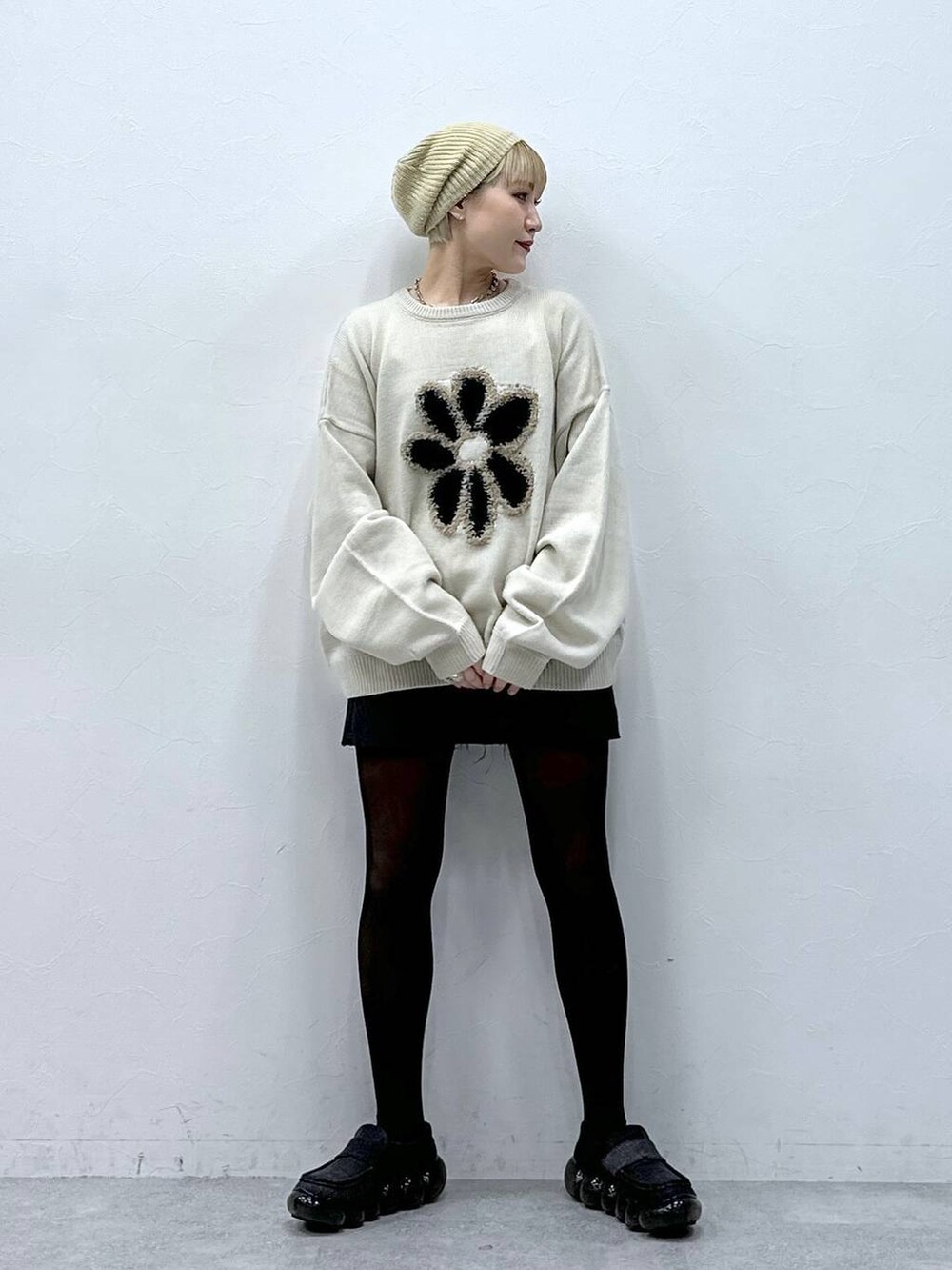 グレー系のスカート、ホワイト系のニット/セーター、ベージュ系のハンチング/ベレー帽を着用したレディースの冬コーディネートの2枚目の写真