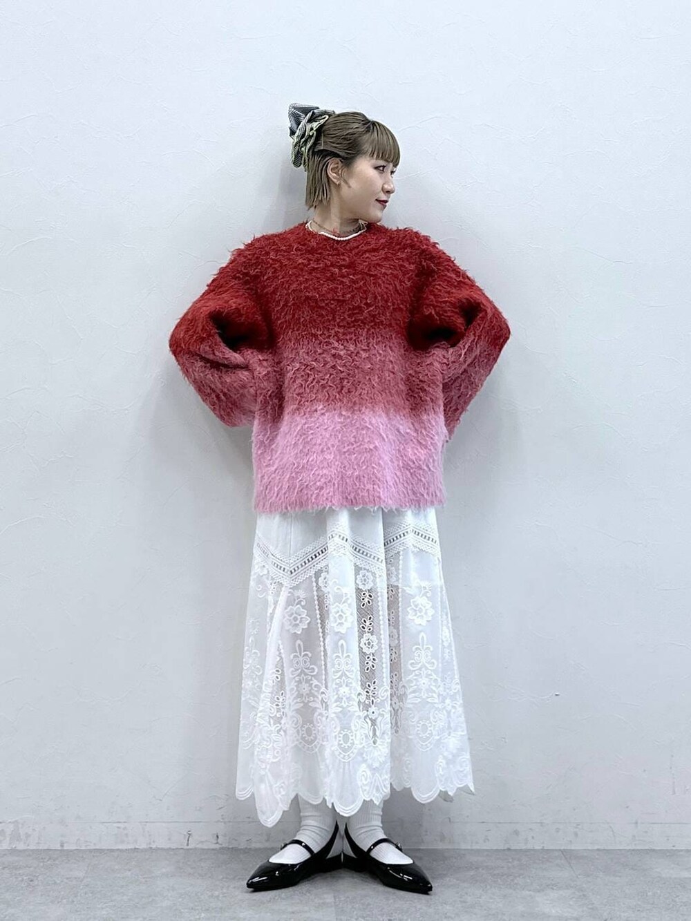 ホワイト系のスカート、レッド系のニット/セーター、ブラック系のパンプスを着用したレディースの冬コーディネートの2枚目の写真