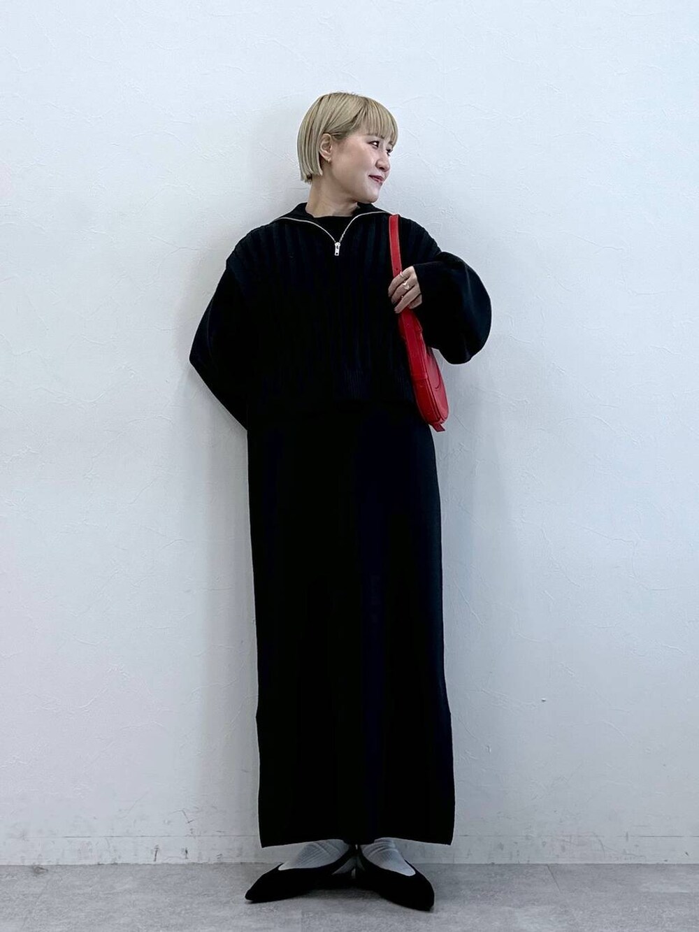 ブラック系のパンプス、レッド系のショルダーバッグ、ブラック系のワンピースを着用したレディースの冬コーディネートの2枚目の写真