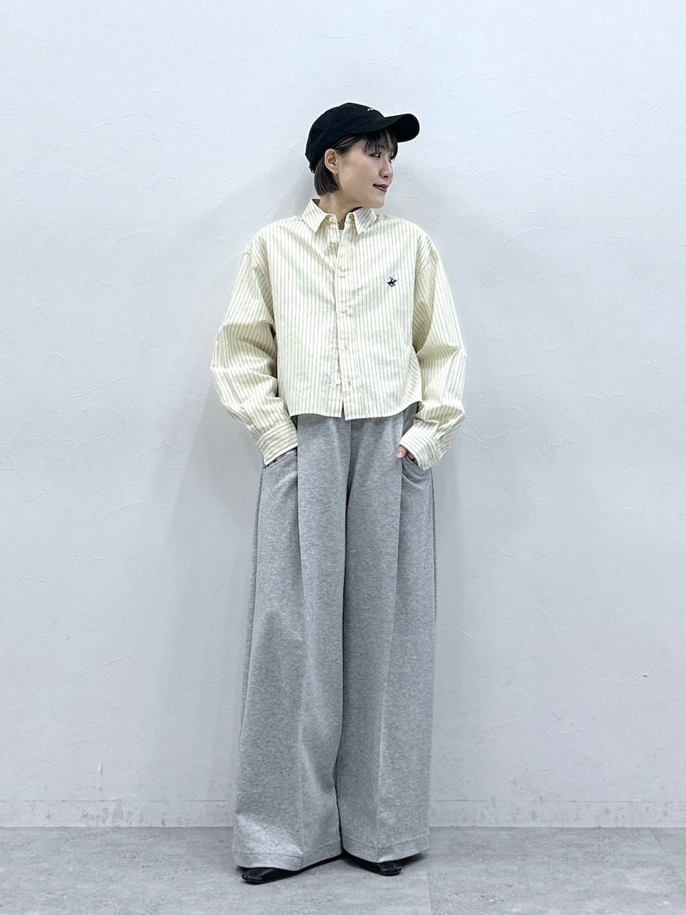 イエロー系のシャツ/ブラウス、グレー系のスウェットパンツ、ブラック系のキャップを着用したレディースの春コーディネートの2枚目の写真