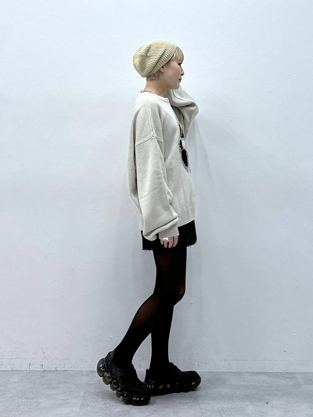 グレー系のスカート、ホワイト系のニット/セーター、ベージュ系のハンチング/ベレー帽を着用したレディースの冬コーディネートの4枚目の写真