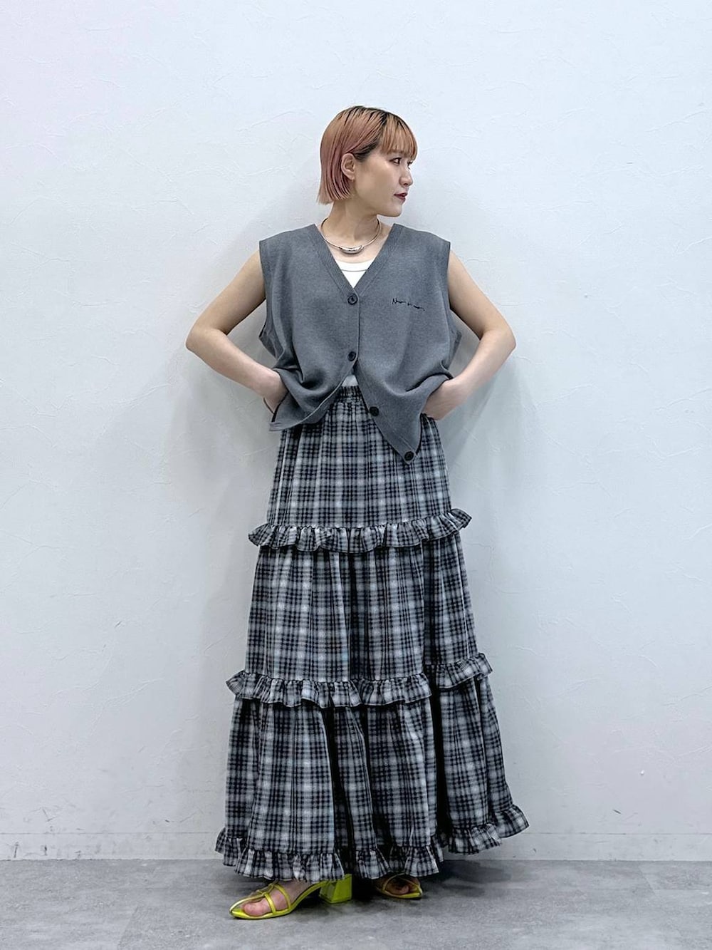 グレー系のベスト、ホワイト系のタンクトップ、ブラック系のスカートを着用したレディースの春コーディネートの4枚目の写真