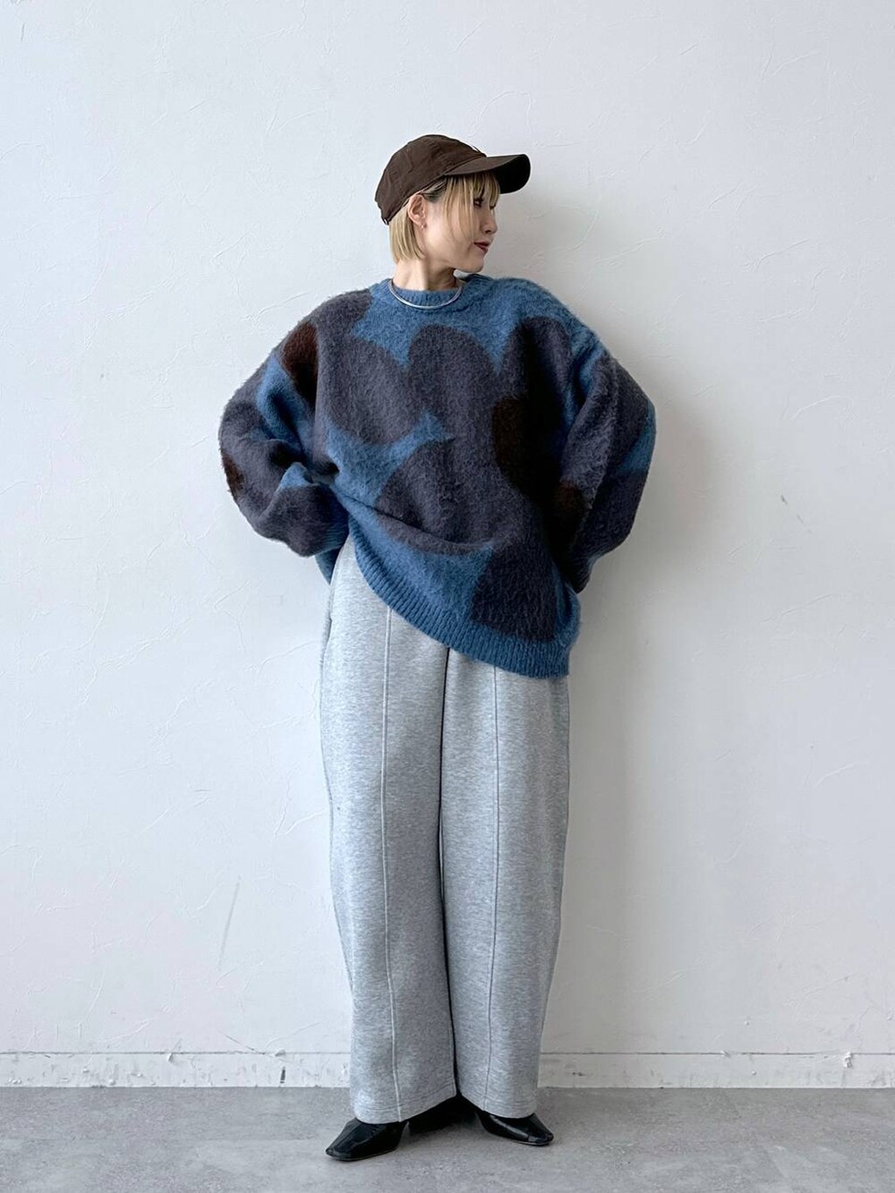 ブルー系のニット/セーター、グレー系のスウェットパンツ、ブラウン系のキャップを着用したレディースの秋コーディネートの2枚目の写真