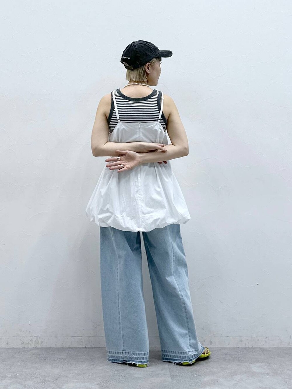 グレー系のタンクトップ、ブルー系のデニムパンツ、ホワイト系のワンピースを着用したレディースの夏コーディネートの7枚目の写真