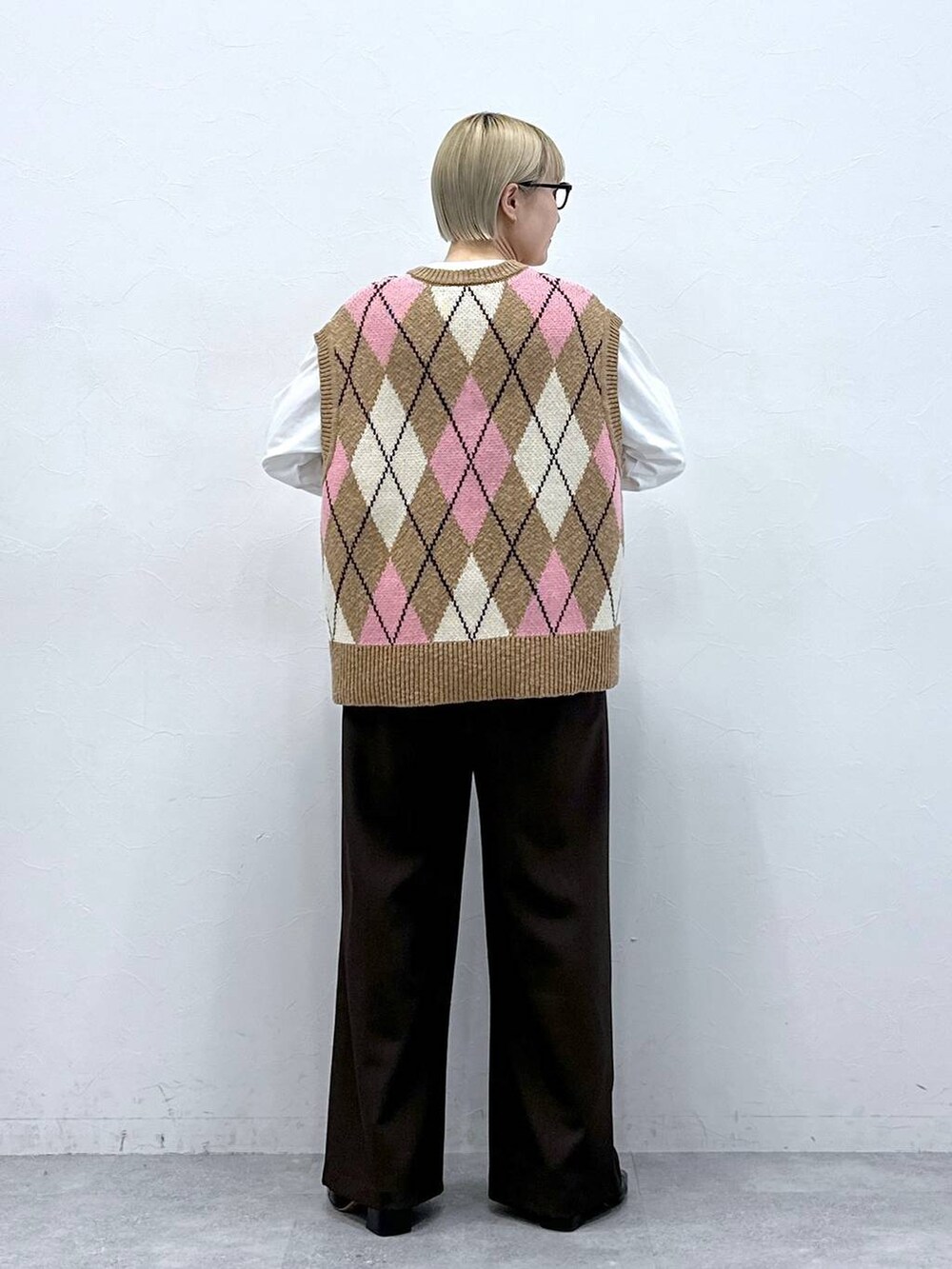 ブラウン系のスラックス、ベージュ系のベスト、ブラック系のサングラスを着用したレディースの冬コーディネートの4枚目の写真