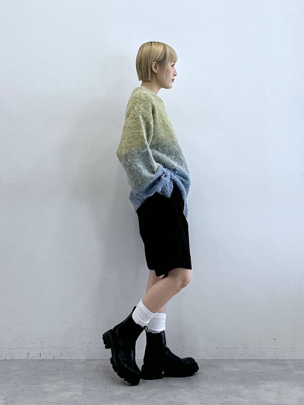 ブラウン系のスラックス、ブラック系のブーツ、イエロー系のニット/セーターを着用したレディースの秋コーディネートの7枚目の写真