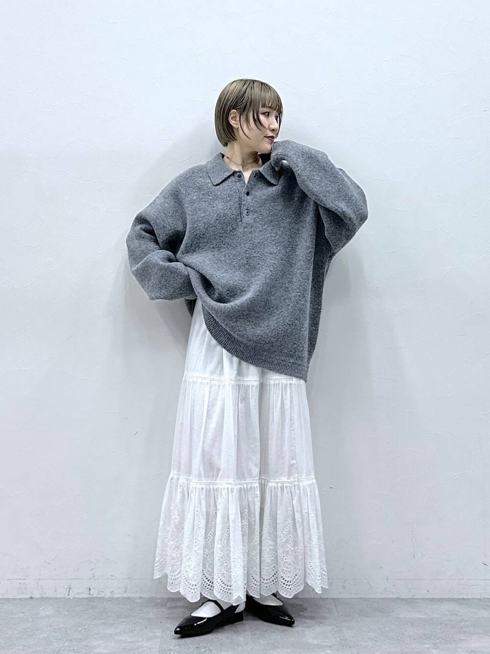 グレー系のポロシャツ、ホワイト系のスカート、ブラック系のパンプスを着用したレディースの冬コーディネートの3枚目の写真