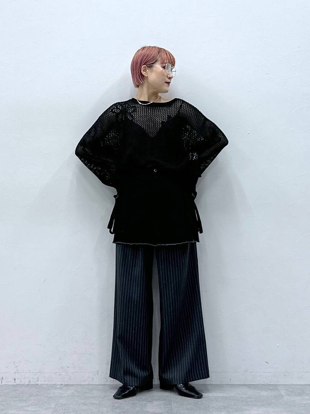 グレー系のスラックス、ブラック系のニット/セーター、ブラック系のスカートを着用したレディースの春コーディネートの4枚目の写真