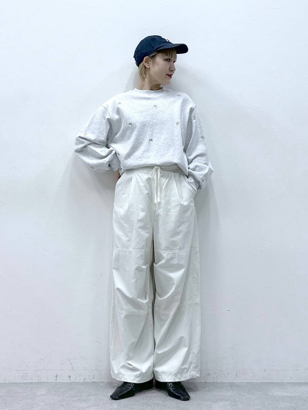 ホワイト系のカーゴパンツ、ホワイト系のスウェット、ブラック系のキャップを着用したレディースの冬コーディネートの3枚目の写真