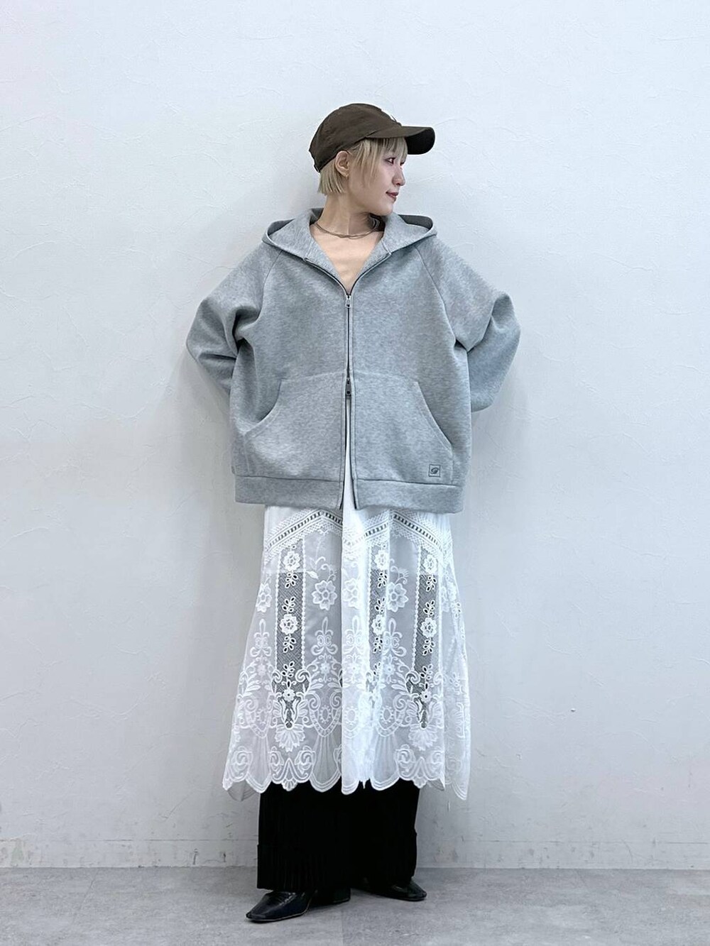 ブラウン系のスラックス、ホワイト系のスカート、グレー系のパーカーを着用したレディースの秋コーディネートの3枚目の写真