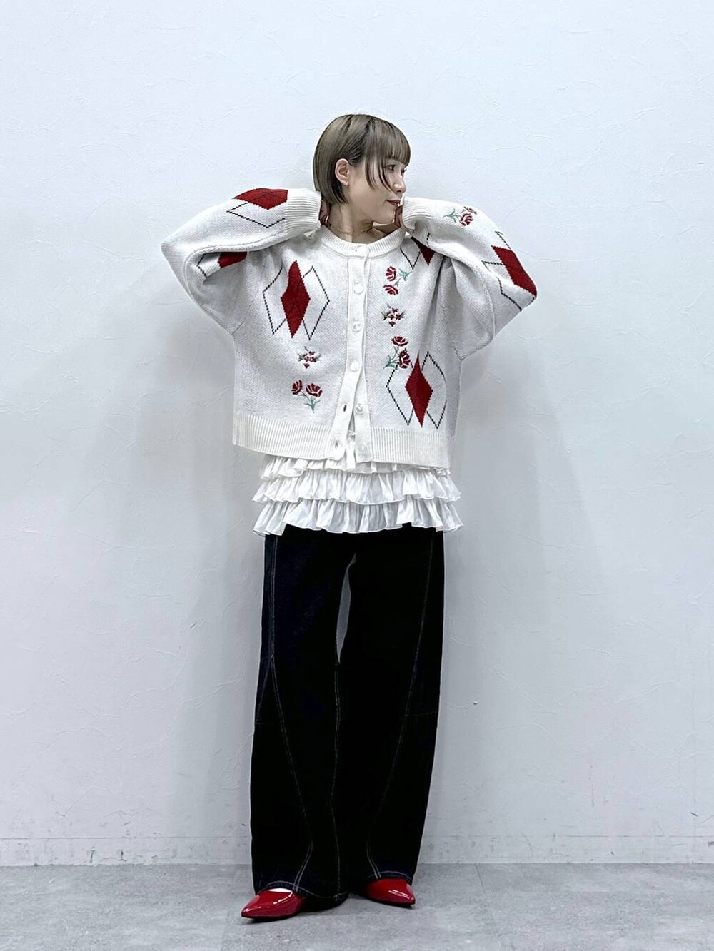 ホワイト系のキャミソール、レッド系のパンプス、ブラック系のデニムパンツを着用したレディースの冬コーディネートの2枚目の写真