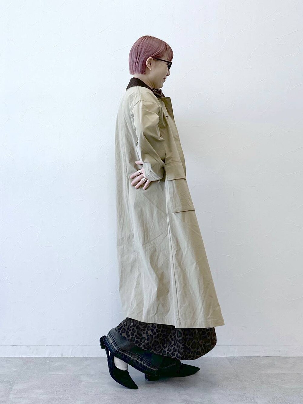 ベージュ系のステンカラーコート、ブラウン系のワンピースを着用したレディースの冬コーディネートの3枚目の写真