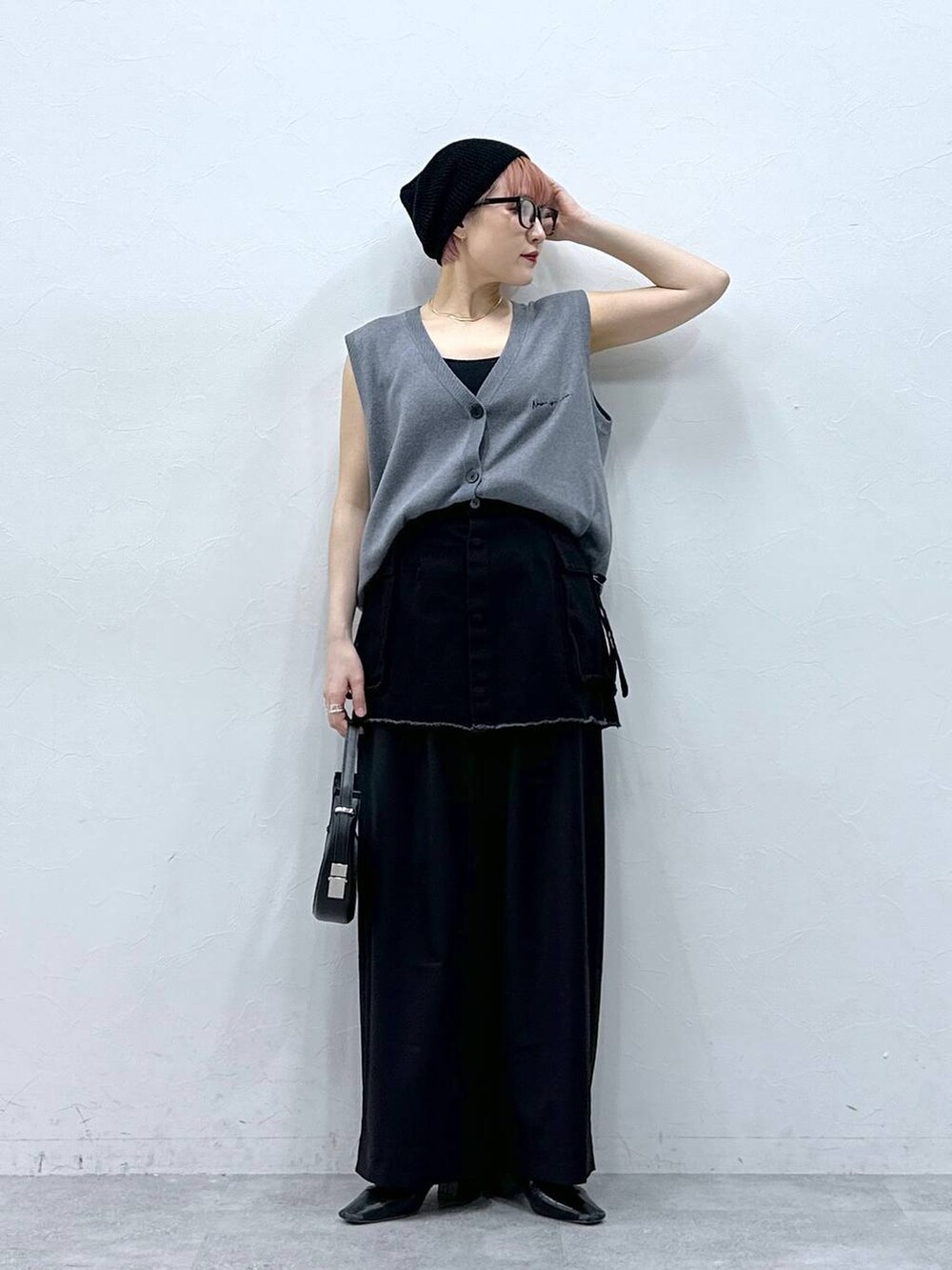 ブラック系のスラックス、ブラック系のスカート、グレー系のベストを着用したレディースの春コーディネートの3枚目の写真