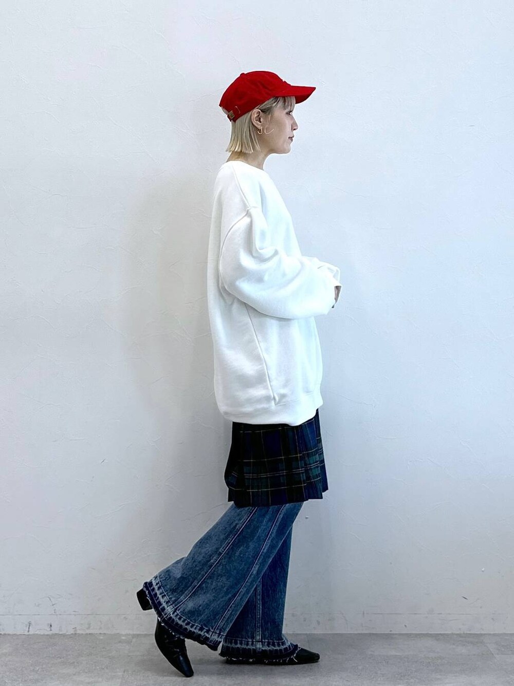 グリーン系のスカート、ブルー系のデニムパンツ、ホワイト系のスウェットを着用したレディースの秋コーディネートの4枚目の写真