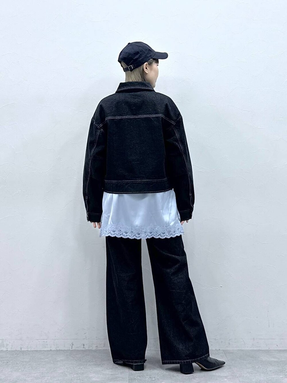 ブラック系のデニムジャケット、ブラック系のデニムパンツ、ブルー系のキャミソールを着用したレディースの冬コーディネートの5枚目の写真