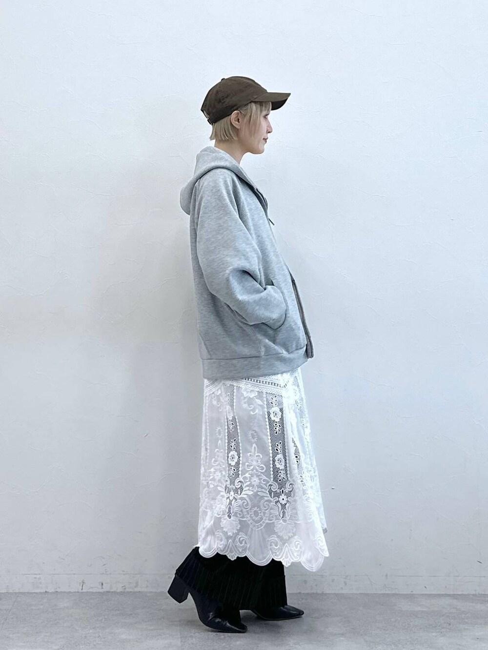 ブラウン系のスラックス、ホワイト系のスカート、グレー系のパーカーを着用したレディースの秋コーディネートの5枚目の写真