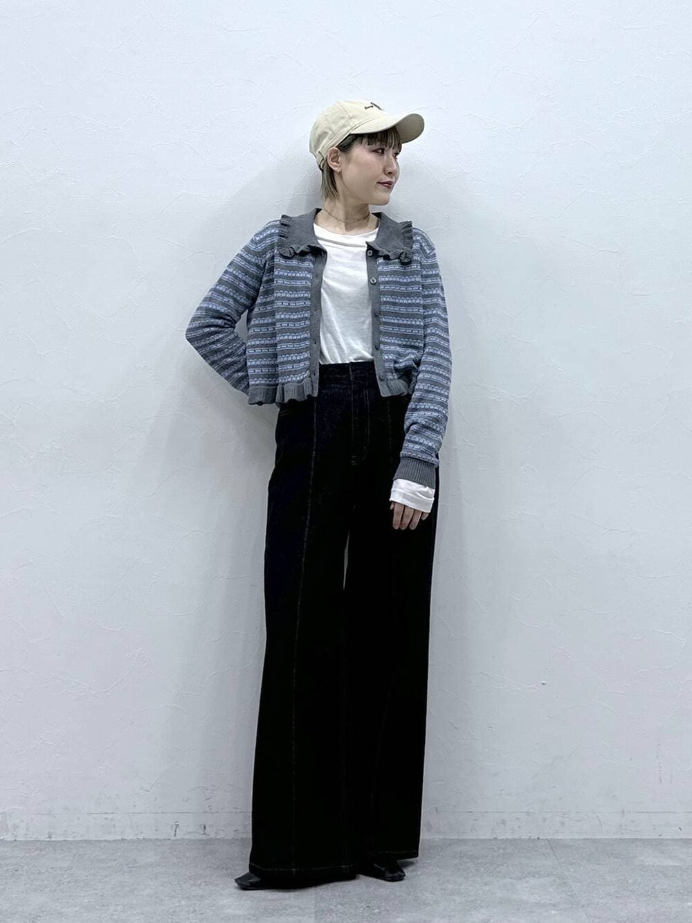 ブラック系のデニムパンツ、ホワイト系のTシャツ/カットソー、グレー系のカーディガン/ボレロを着用したレディースの冬コーディネートの2枚目の写真