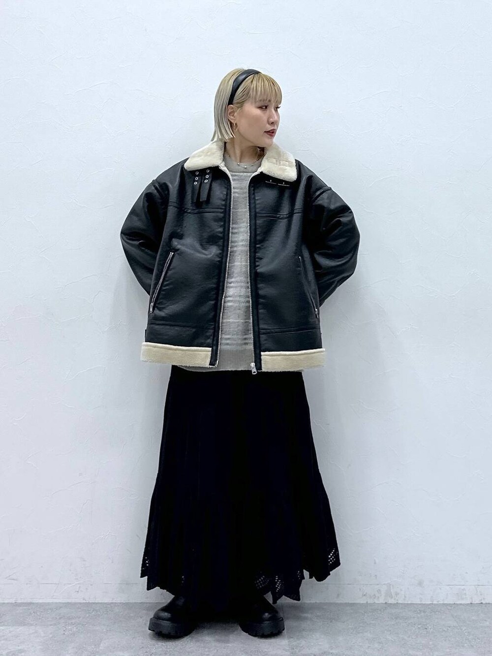 ブラック系のムートンコート、ブラック系のブーツ、ブラック系のスカートを着用したレディースの秋コーディネートの2枚目の写真