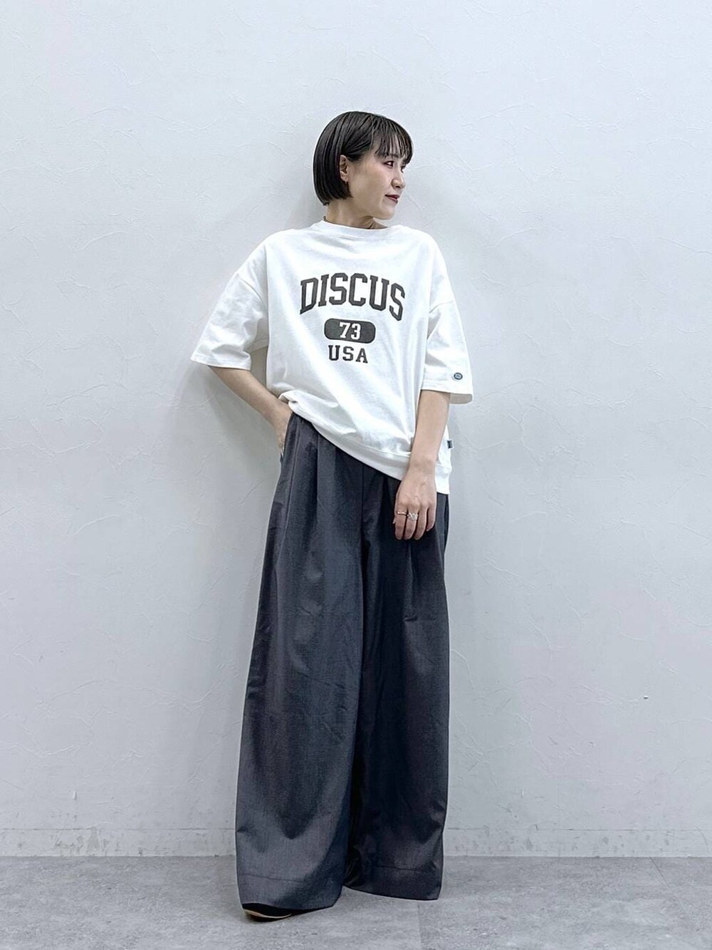 ホワイト系のTシャツ/カットソー、グレー系のスラックスを着用したレディースの春コーディネートの2枚目の写真