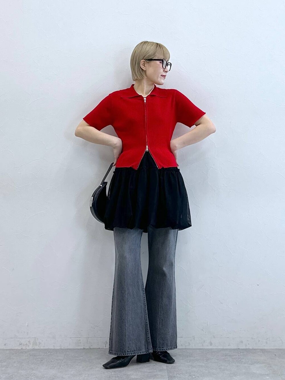 レッド系のニット/セーター、グレー系のデニムパンツ、ブラック系のスカートを着用したレディースの夏コーディネートの3枚目の写真