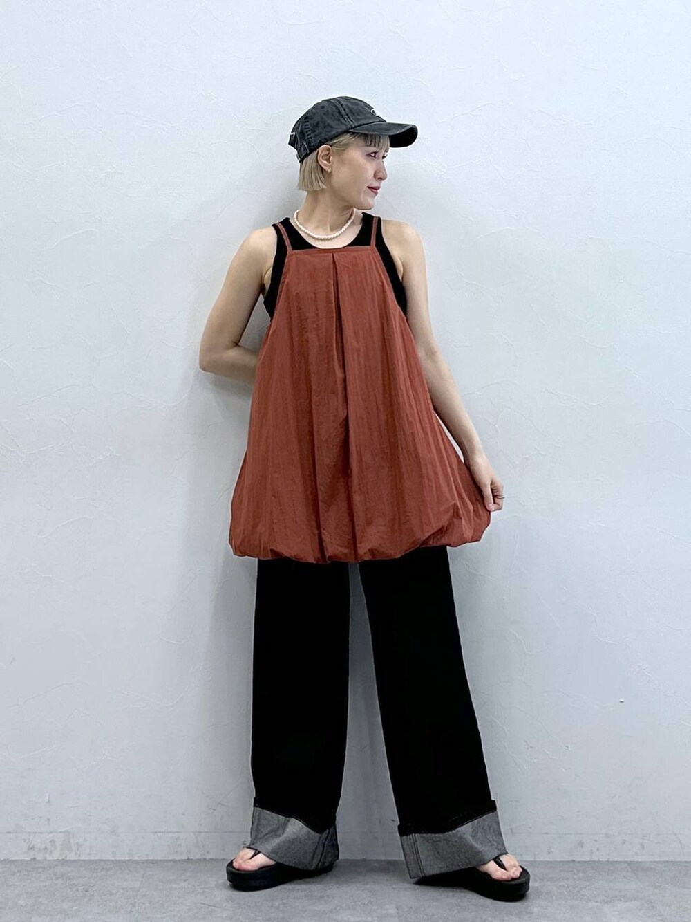 ブラウン系のワンピース、ブラック系のデニムパンツ、ブラック系のキャップを着用したレディースの夏コーディネートの2枚目の写真