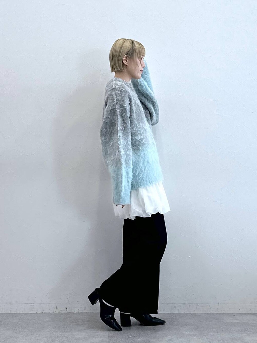 ブラック系のデニムパンツ、ホワイト系のスカート、グレー系のニット/セーターを着用したレディースの秋コーディネートの4枚目の写真