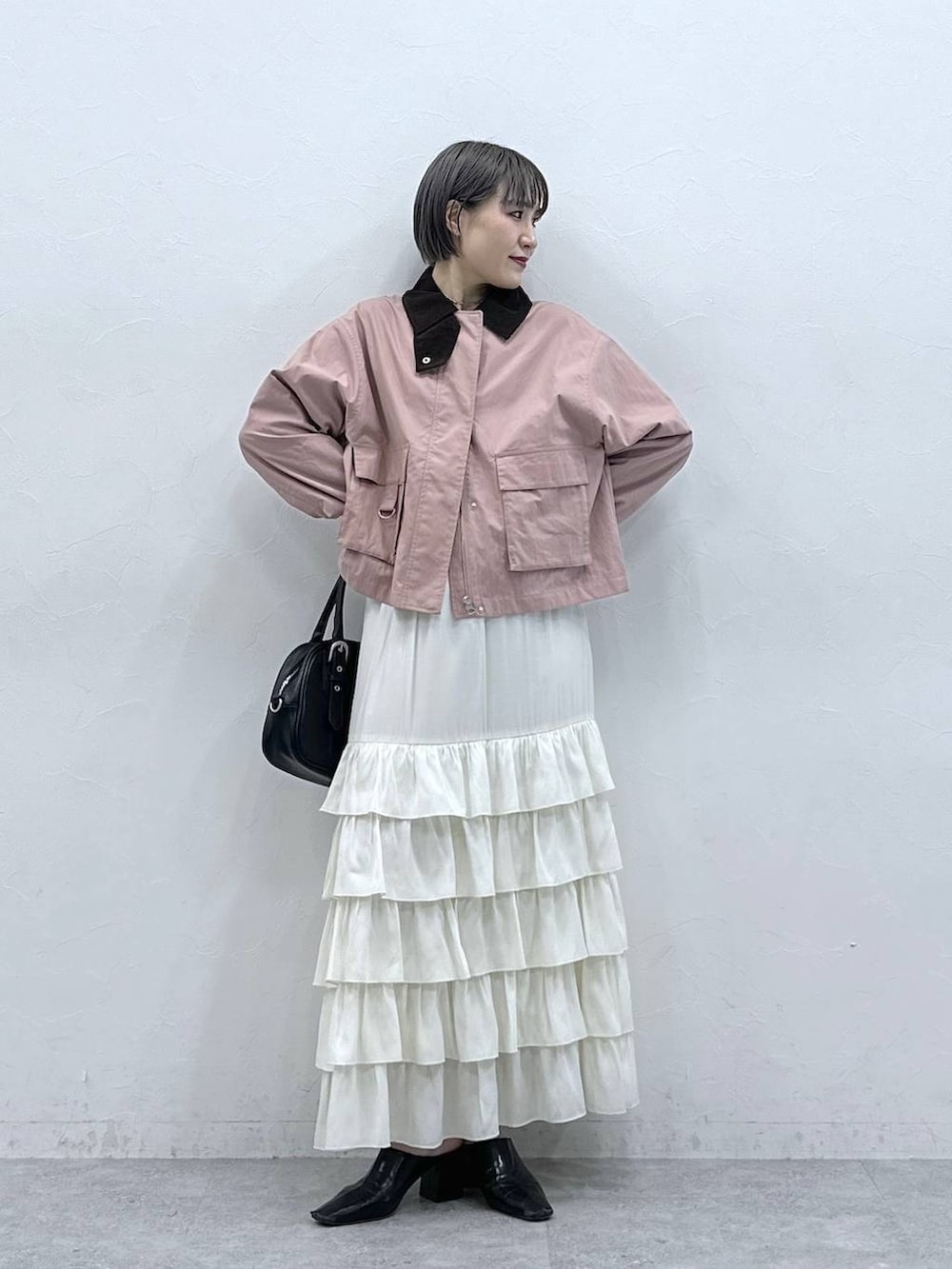 ピンク系のブルゾン、ホワイト系のスカートを着用したレディースの春コーディネートの2枚目の写真