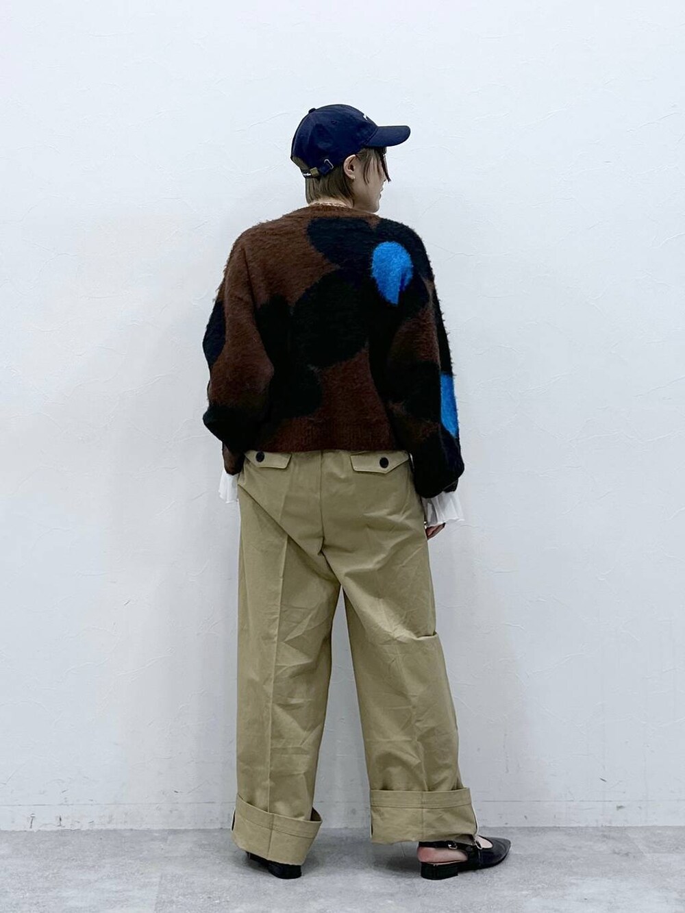 ブラウン系のニット/セーター、ブラック系のパンプス、ベージュ系のチノパンツを着用したレディースの冬コーディネートの5枚目の写真