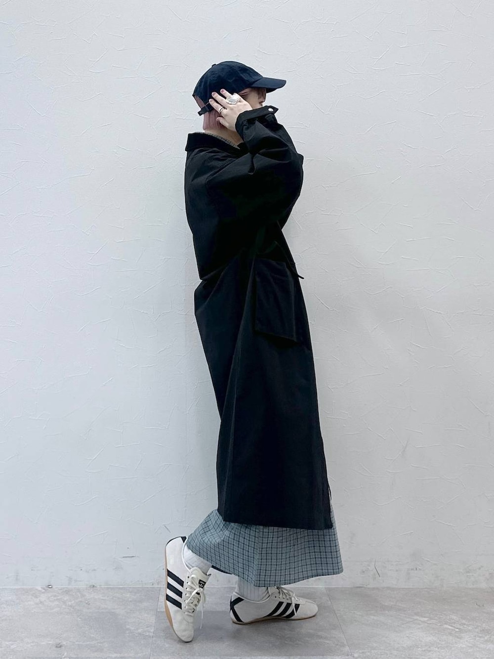 ブラック系のステンカラーコート、ホワイト系のスニーカー、ブルー系のシャツワンピースを着用したレディースの冬コーディネートの4枚目の写真