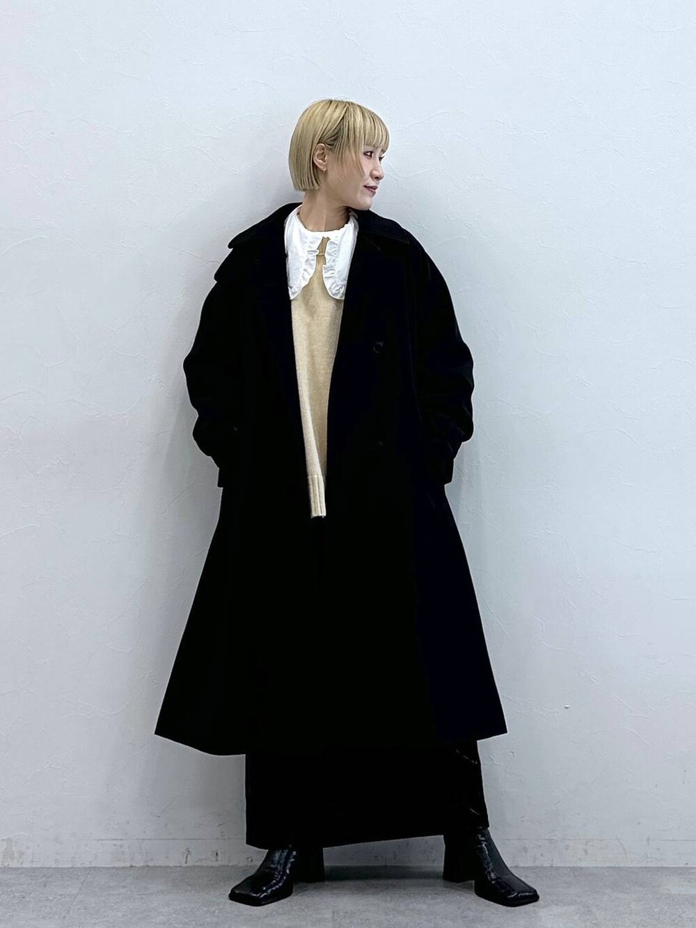 ブラック系のステンカラーコート、ホワイト系のTシャツ/カットソー、ブラック系のスカートを着用したレディースの秋コーディネートの3枚目の写真