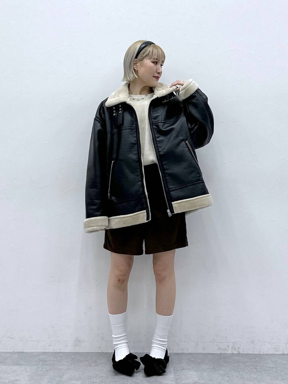 ブラック系のパンプス、ホワイト系のニット/セーター、ブラック系のムートンコートを着用したレディースの秋コーディネートの3枚目の写真