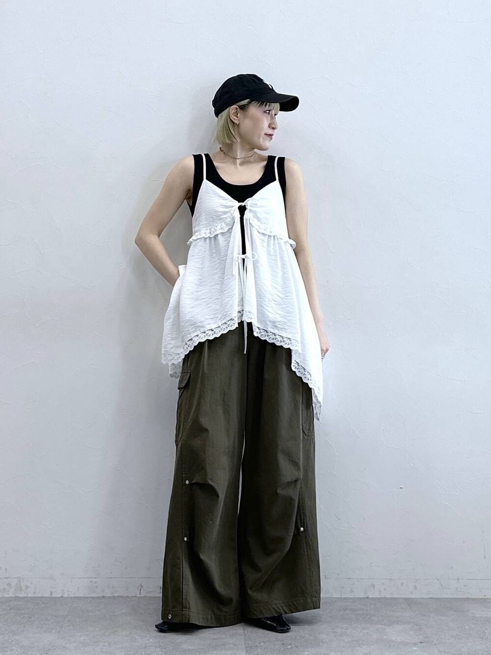 グリーン系のカーゴパンツ、ブラック系のタンクトップ、ホワイト系のキャミソールを着用したレディースの夏コーディネートの2枚目の写真