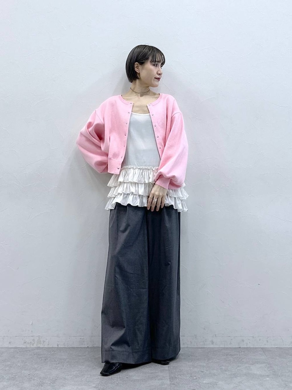 ホワイト系のキャミソール、ピンク系のカーディガン/ボレロ、グレー系のスラックスを着用したレディースの春コーディネートの2枚目の写真