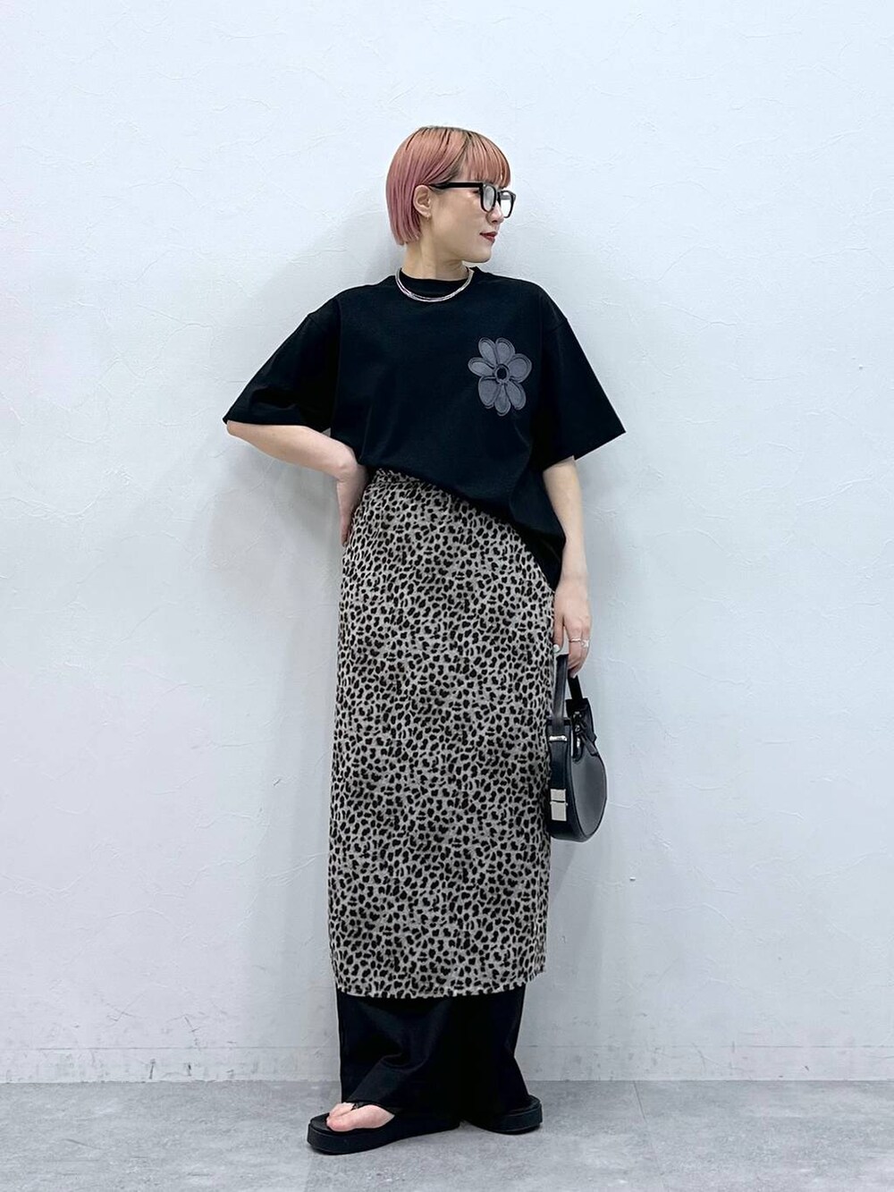 ブラック系のスラックス、ブラック系のTシャツ/カットソー、ベージュ系のスカートを着用したレディースの春コーディネートの2枚目の写真