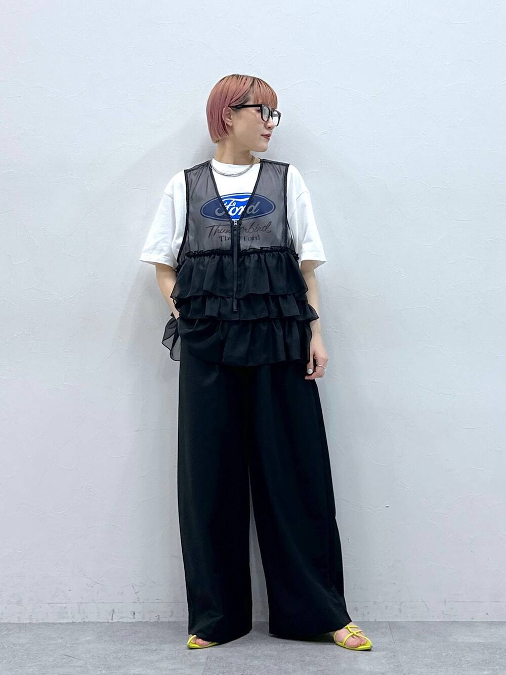 ブラック系のスラックス、ホワイト系のTシャツ/カットソー、ブラック系のベストを着用したレディースの春コーディネートの2枚目の写真