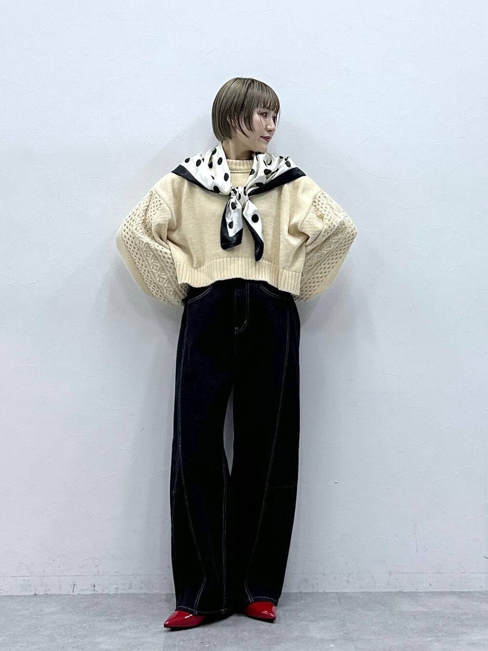 ホワイト系のニット/セーター、レッド系のパンプス、ブラック系のデニムパンツを着用したレディースの冬コーディネートの4枚目の写真