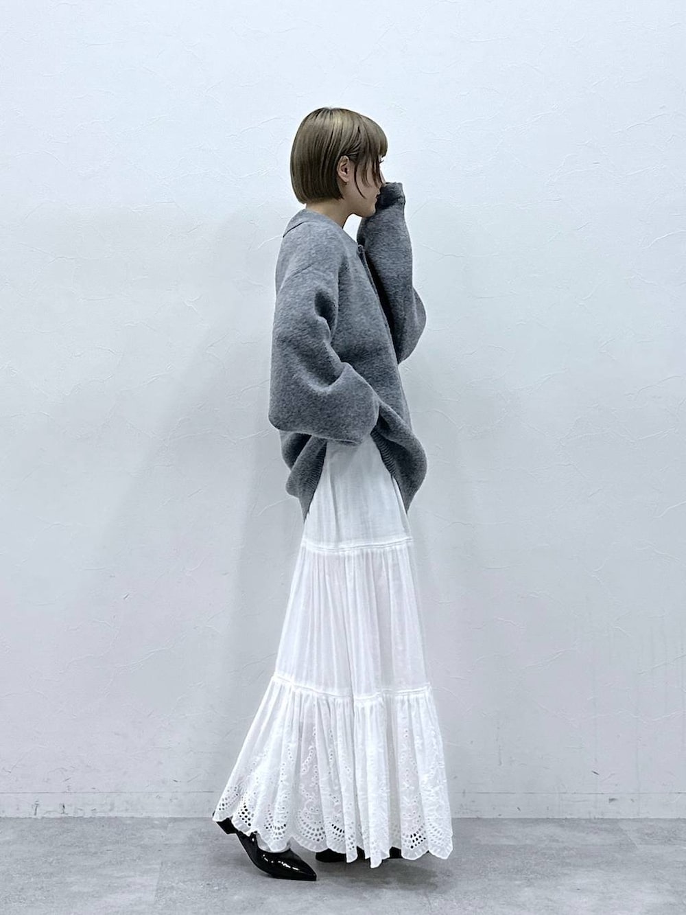 グレー系のポロシャツ、ホワイト系のスカート、ブラック系のパンプスを着用したレディースの冬コーディネートの5枚目の写真