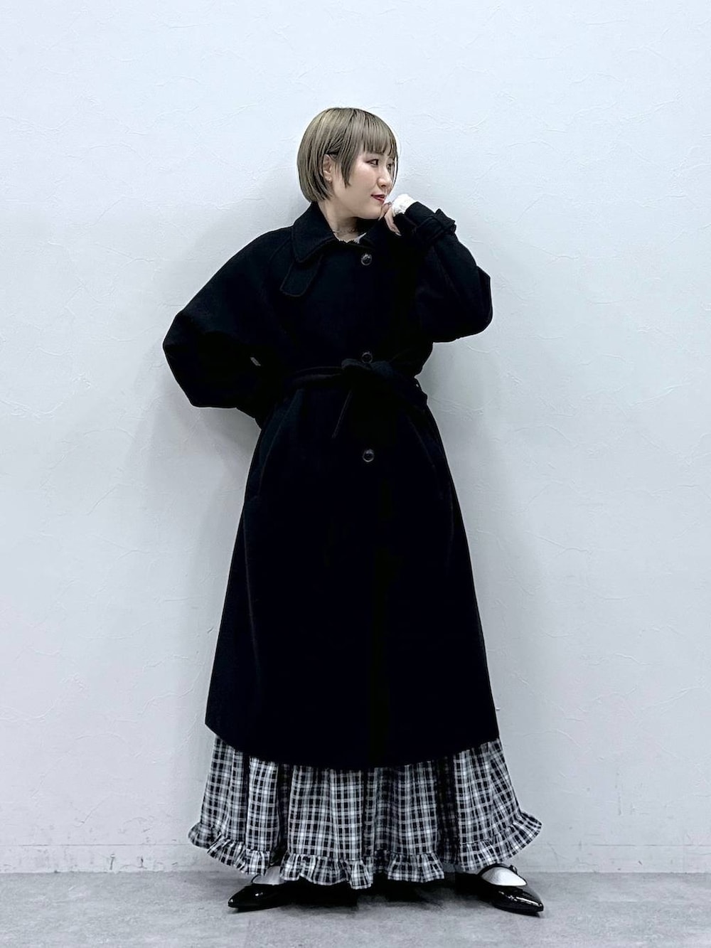 ブラック系のステンカラーコート、ブラック系のスカート、ブラック系のパンプスを着用したレディースの冬コーディネートの4枚目の写真
