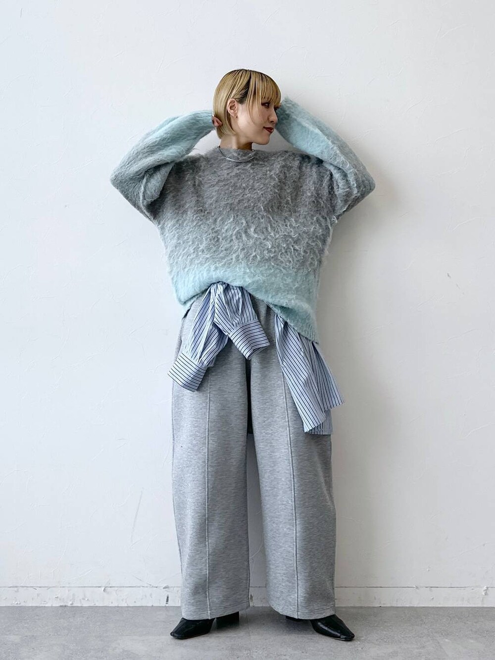 グレー系のニット/セーター、ブルー系のTシャツ/カットソー、グレー系のスウェットパンツを着用したレディースの秋コーディネートの2枚目の写真
