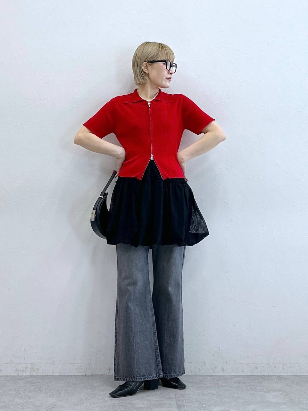 レッド系のニット/セーター、グレー系のデニムパンツ、ブラック系のスカートを着用したレディースの夏コーディネートの5枚目の写真