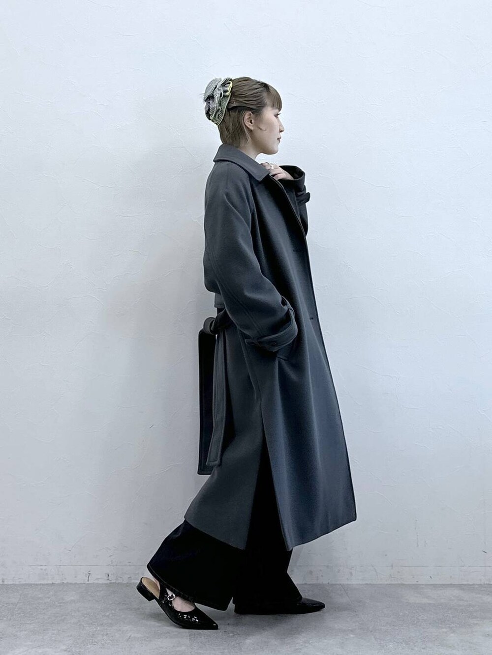 グレー系のステンカラーコート、ブラック系のニット/セーター、ブラック系のパンプスを着用したレディースの冬コーディネートの6枚目の写真