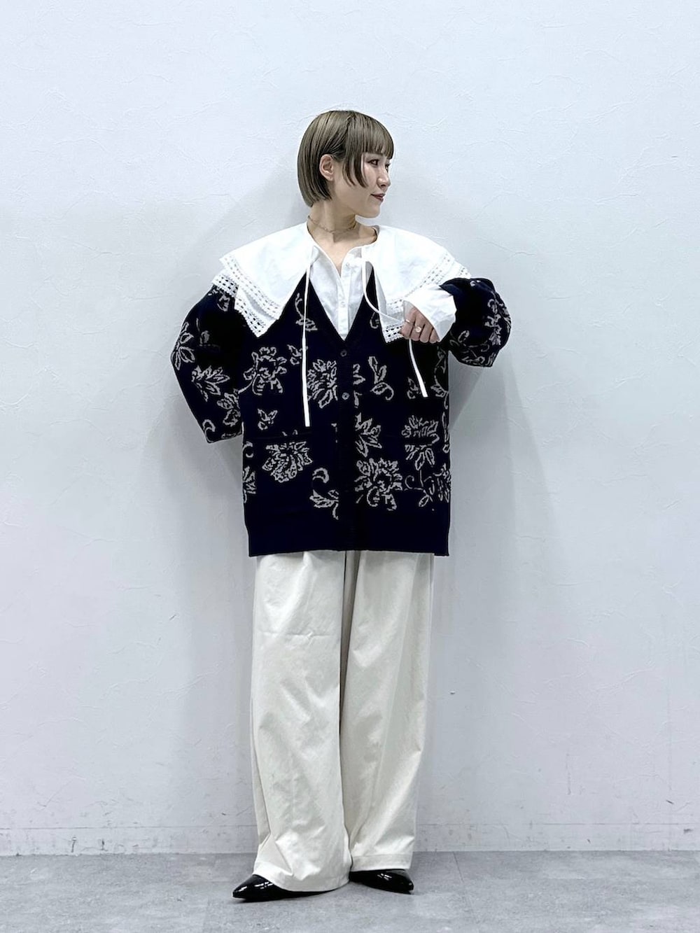 ホワイト系のチノパンツ、ホワイト系のシャツ/ブラウス、ブルー系のニット/セーターを着用したレディースの冬コーディネートの2枚目の写真