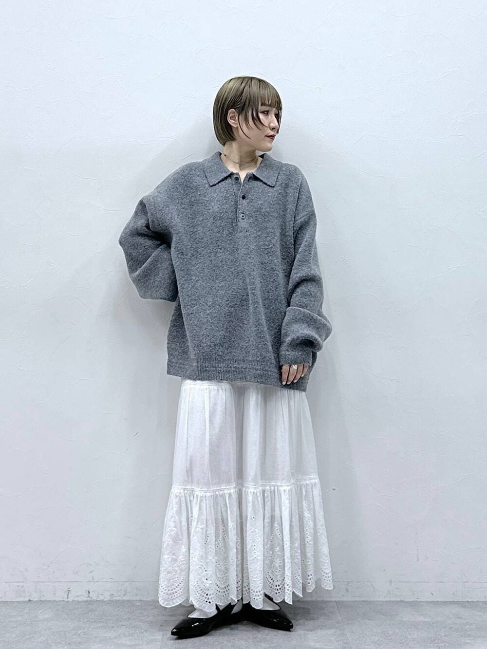 グレー系のポロシャツ、ホワイト系のスカート、ブラック系のパンプスを着用したレディースの冬コーディネートの4枚目の写真