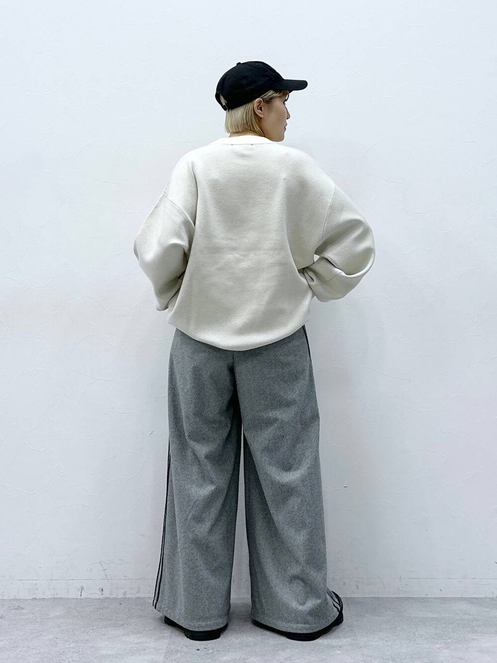 ブラック系のスラックス、ホワイト系のニット/セーターを着用したレディースの冬コーディネートの5枚目の写真