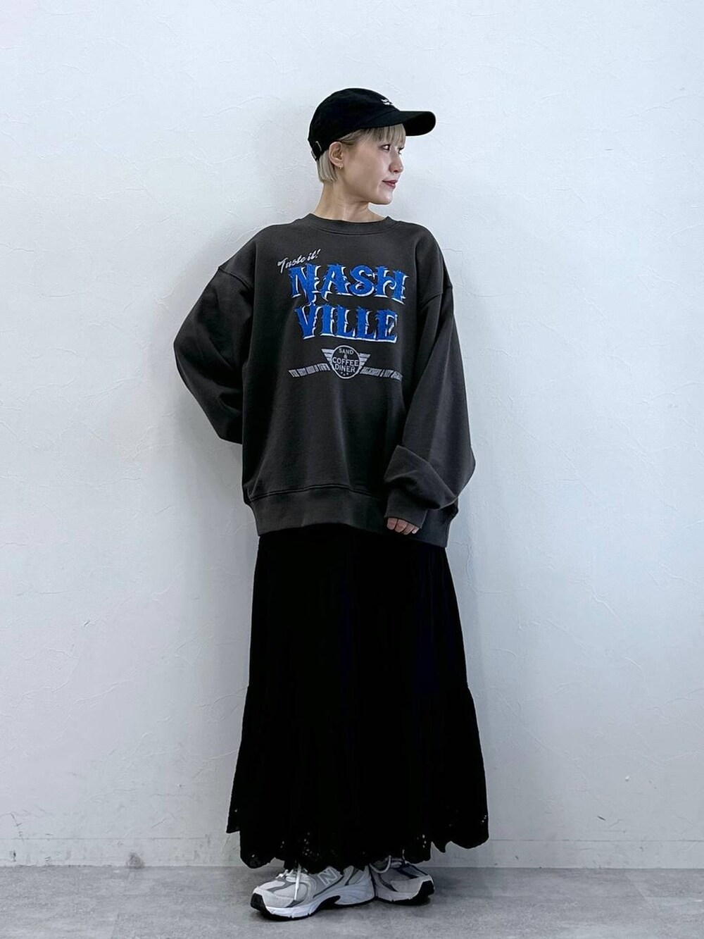 ブラック系のスウェット、ブラック系のスカート、ブラック系のキャップを着用したレディースの冬コーディネートの2枚目の写真