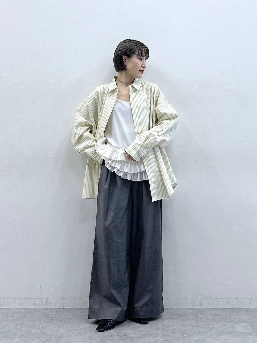 ホワイト系のキャミソール、イエロー系のシャツ/ブラウス、グレー系のスラックスを着用したレディースの春コーディネートの2枚目の写真